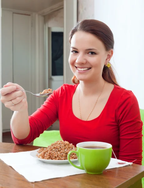 Ragazza felice mangia grano saraceno a casa — Foto Stock