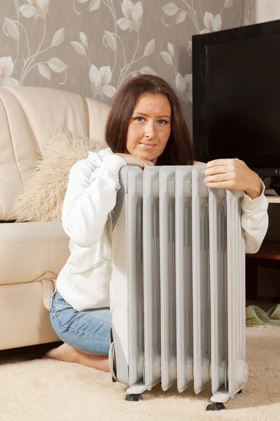 Vrouw bij warme radiator in huis — Stockfoto