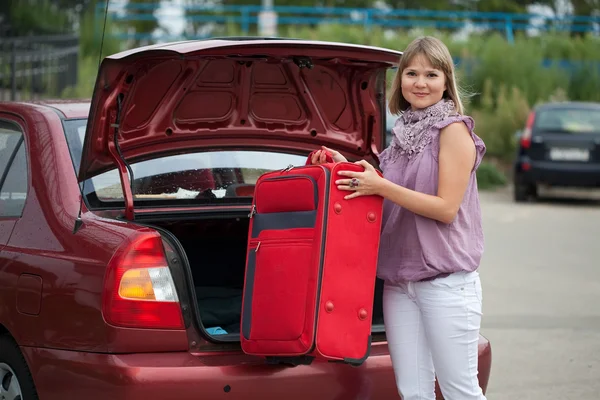 Meisje zet koffer in de trunk — Stockfoto