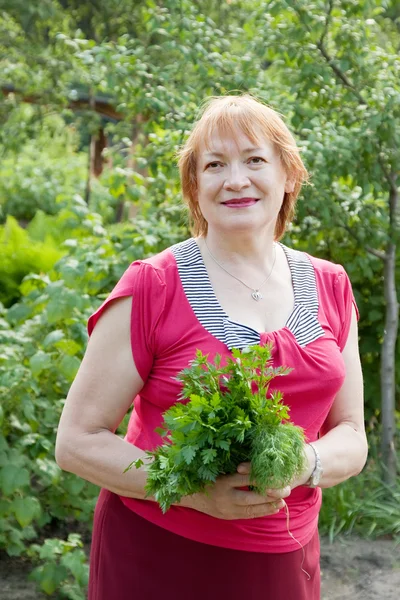 Mature woman with dill and parsley — Stock Photo, Image