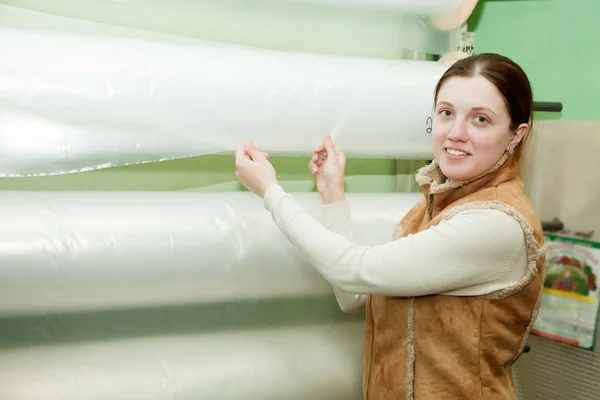 Woman chooses polythene at foil roll — Stock Photo, Image