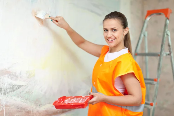 Smiling woman paints wall — Stock Photo, Image