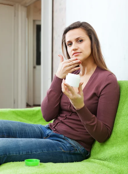 Mujer hermosa pone crema en la cara — Foto de Stock