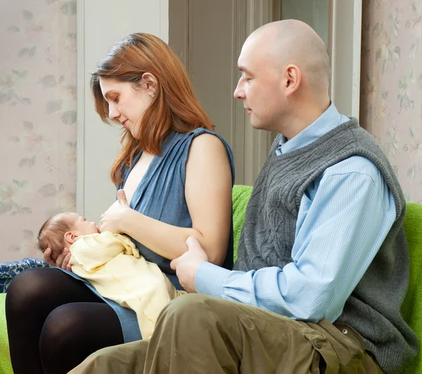 Father looks at the baby sucking breast of mother — Stock Photo, Image