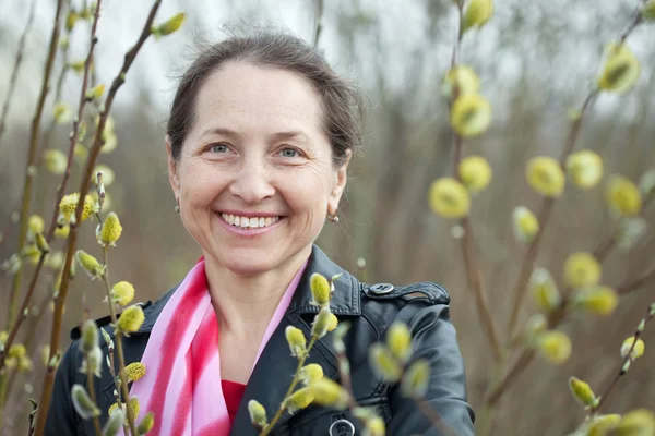 Mulher madura na primavera pussywillow planta — Fotografia de Stock