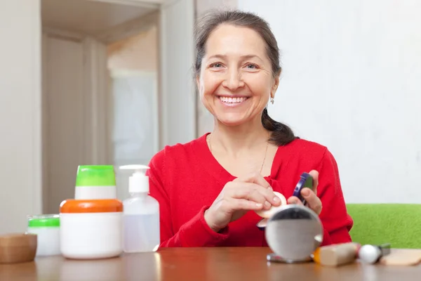 Mature woman puts facepowder — Stock Photo, Image