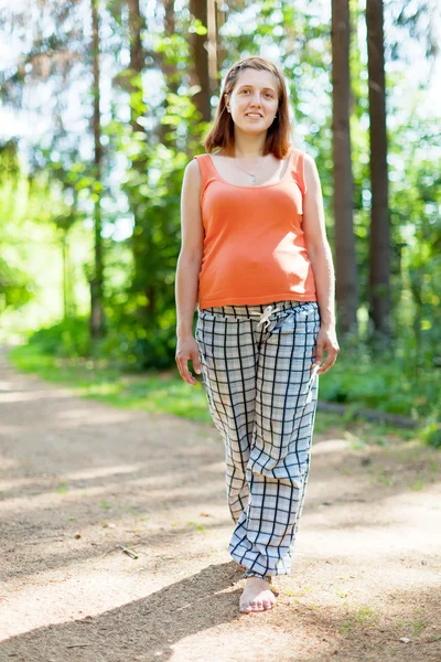 Mulher grávida caminha na estrada da floresta — Fotografia de Stock