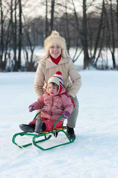 Child on sled with mother in winter — Stockfoto