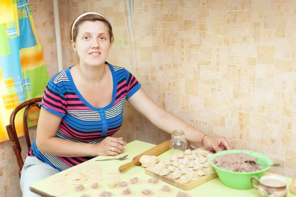 Woman making dumplings (pelmeni) in kitchen — Stock Photo, Image