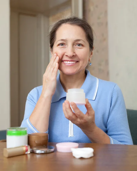 Reife Frau setzt Creme auf Gesicht — Stockfoto