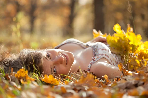 Jonge vrouw ligt in herfst park — Stockfoto