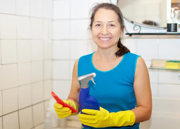 Mujer limpia cuarto de baño con alfombra y limpiador — Foto de Stock