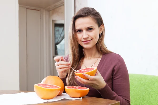 Menina de cabelos longos come toranja em casa — Fotografia de Stock