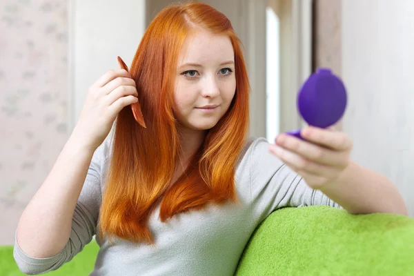 Red-haired girl combing hair — Stock Photo, Image