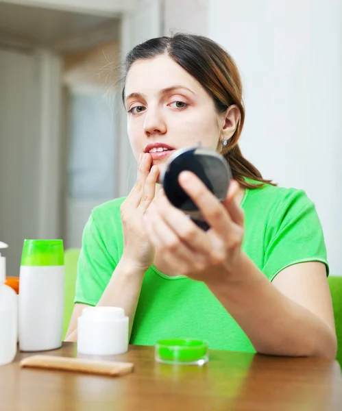 Girl in green stares on face in mirror — Stock Photo, Image