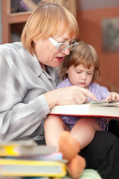 Grootmoeder en kind leest boek — Stockfoto