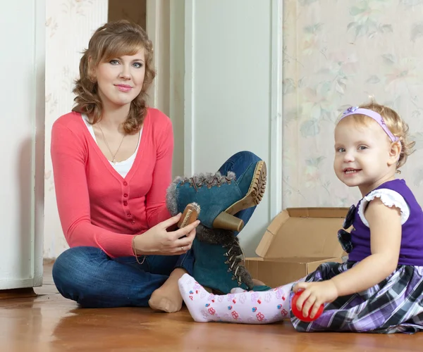 Vrouw met babymeisje reinigt schoeisel — Stockfoto