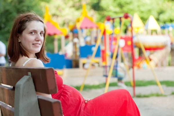 Pregnancy woman against playground — Stock Photo, Image