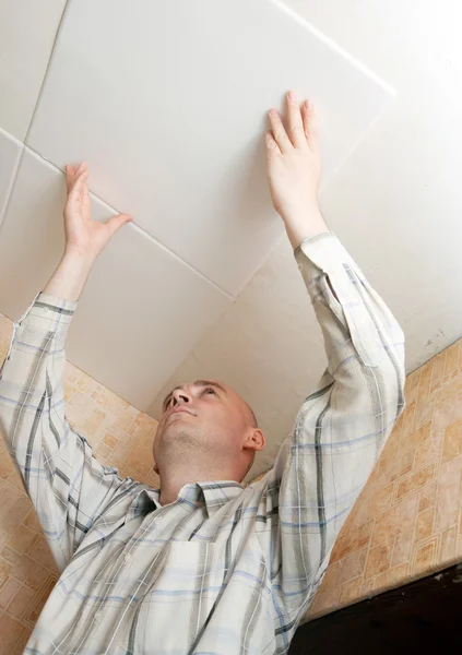 Uomo incolla mattonelle soffitto — Foto Stock