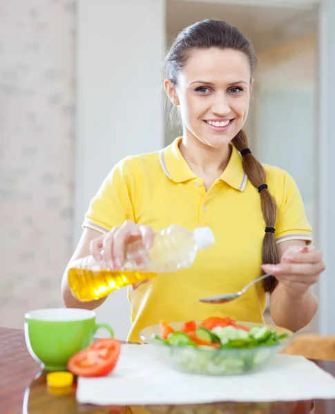 Mujer feliz vertiendo aceite de botella en ensalada —  Fotos de Stock