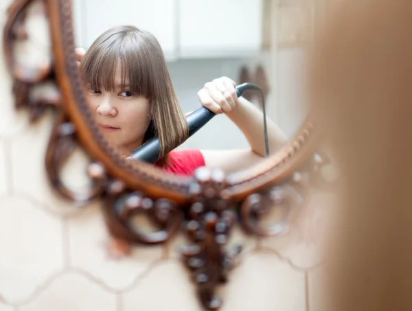 Gadis menggunakan pengeriting rambut sebelum cermin — Stok Foto