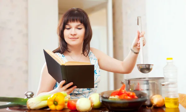 Hemmafru matlagning med bok — Stockfoto