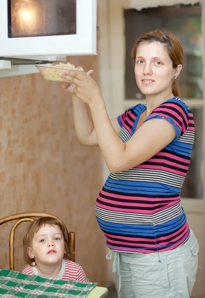 Pregnant woman warms up food — Stock Photo, Image