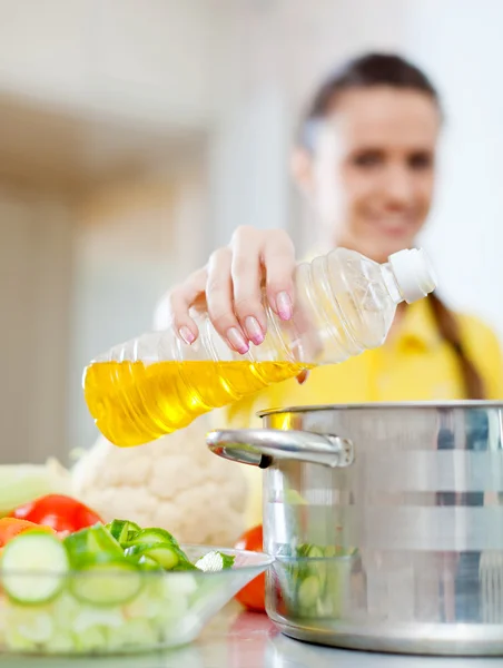 Mujer en amarillo vierte aceite en una cacerola —  Fotos de Stock