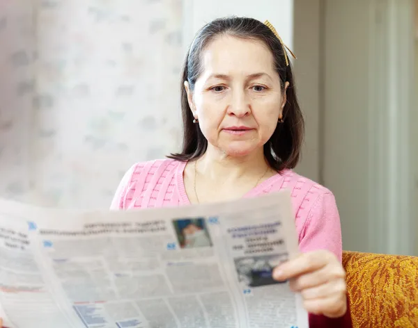 Серьезная женщина читает газету — стоковое фото