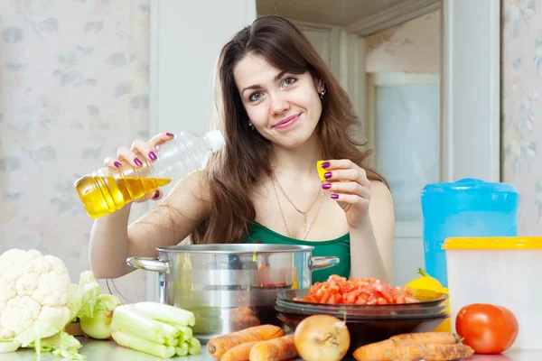 Bella casalinga cucinare verdure con olio — Foto Stock