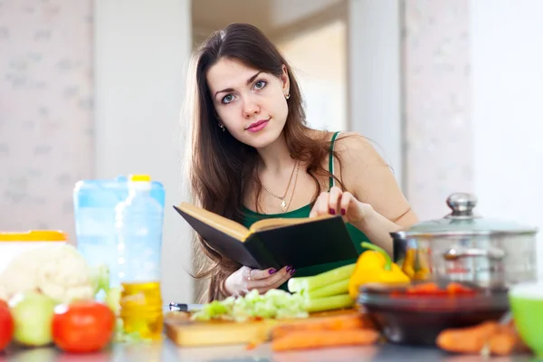 Ung kvinna läser kokbok för recept — Stockfoto