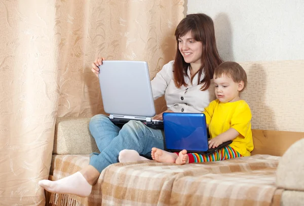 Donna felice con bambino utilizzando i computer portatili in soggiorno — Foto Stock