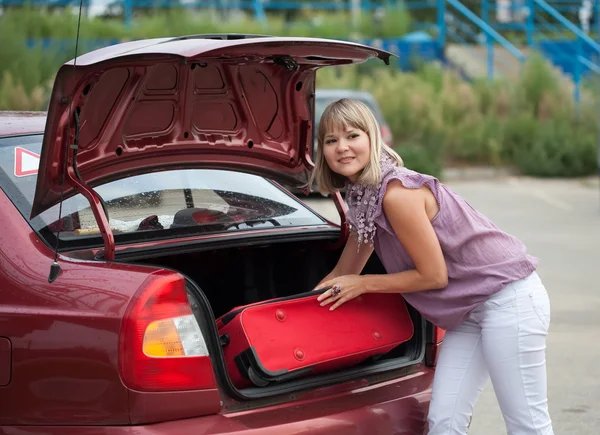 Meisje zet de koffer in auto — Stockfoto