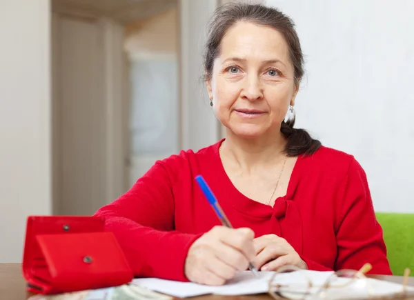 Serious mature woman fills bills — Stock Photo, Image