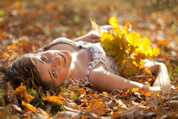 Woman lies in oak leaves — Stock Photo, Image