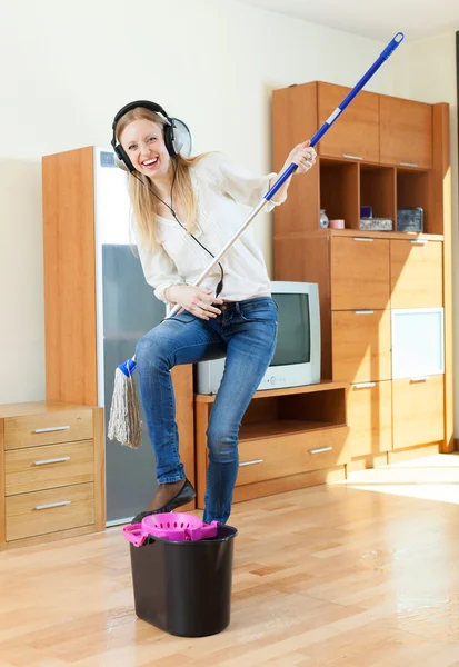 Feliz dona de casa em fones de ouvido chão de lavagem — Fotografia de Stock