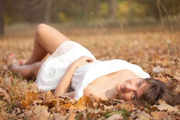 Meşe yaprağı içinde genç bir kadın yatıyor — Stok fotoğraf