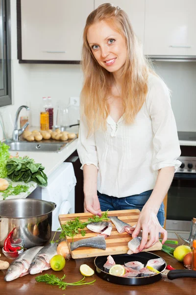 Woman putting pieces of saltwater fish into frying pan — Stock Photo, Image