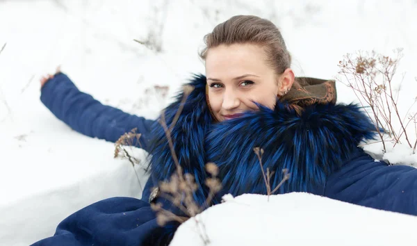 Menina bonita feliz deitada na neve — Fotografia de Stock