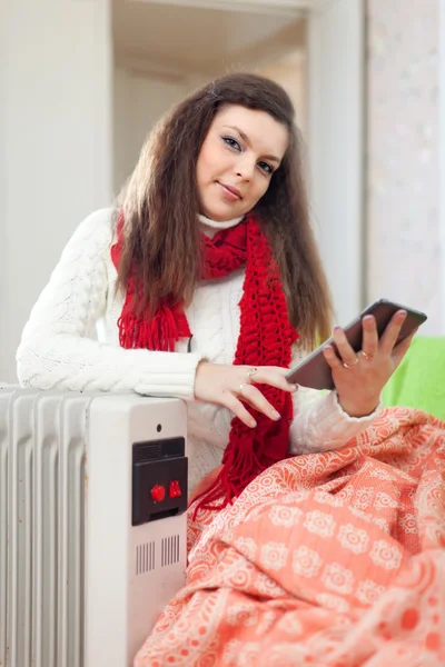 Woman reads e-book near heater — Stock Photo, Image