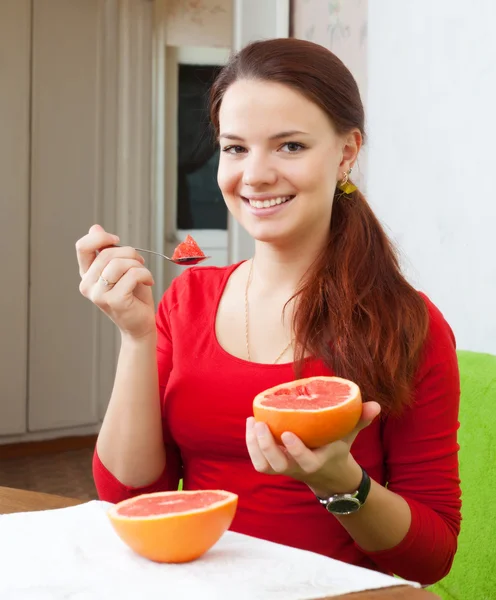 Menina em vermelho come toranja com colher — Fotografia de Stock