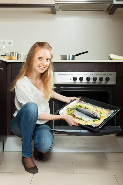 女人在烤箱烹饪鱼 — 图库照片