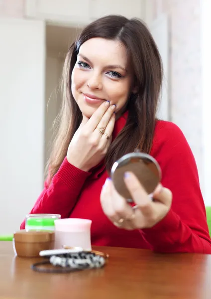 Woman looks on her face in mirror — Stock Photo, Image