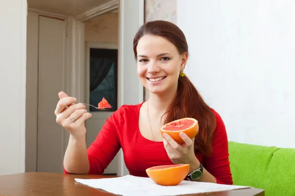 Langharige vrouw in het rood eet grapefruit — Stockfoto