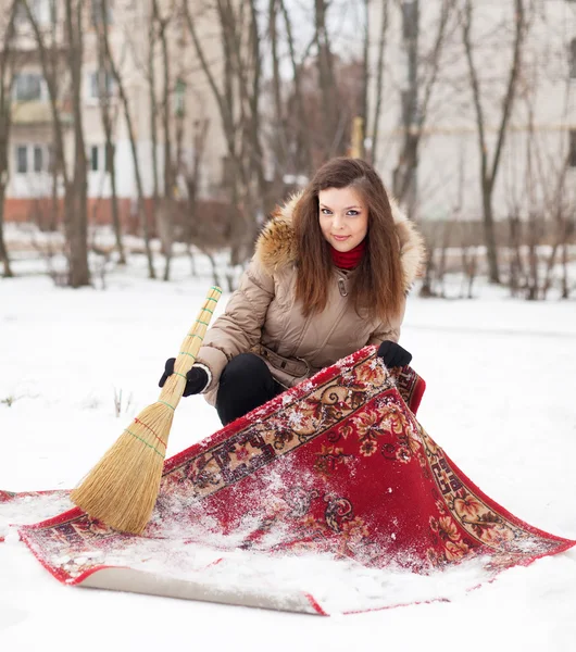 Ragazza pulisce tappeto con neve — Foto Stock