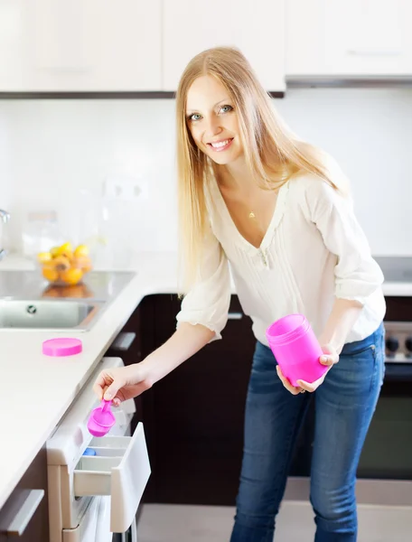 Blond kvinna gör tvätt med rengöringsmedel — Stockfoto