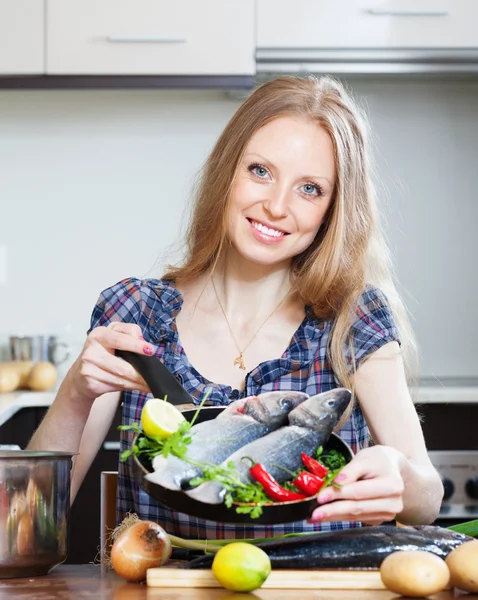 Smiling blonde woman cooking lubina in frying pan — Stock Photo, Image