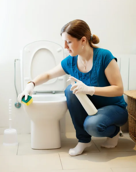 Vrouw schoonmaken toilet met een spons en schonere — Stockfoto