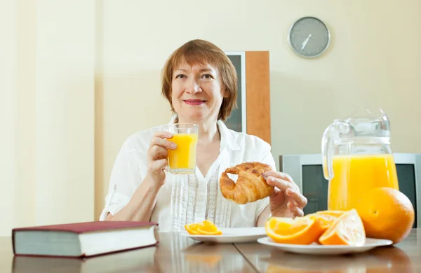 Mature woman having breakfast with juice — Stock Photo, Image