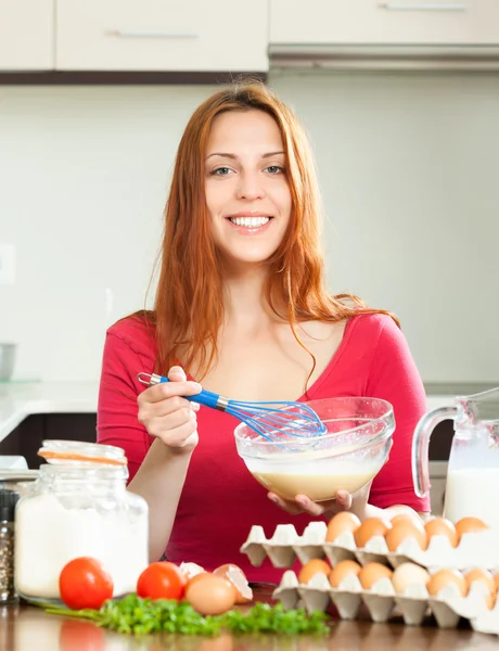 Dona de casa sorridente em vermelho fazendo massa com leite — Fotografia de Stock